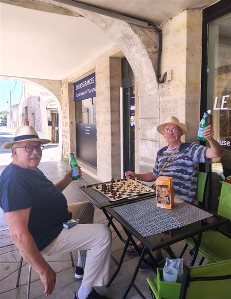 Un échiquier, une table, deux chaises et deux amis des échecs sous les arcades de Créon